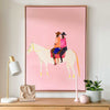 Oak framed Lottie Rae Smooth Operator fine art canvas print with pink background and two figures riding a white horse on a wooden surface with decorative objects