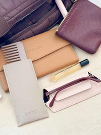 Fox and Leo tan leather travel organiser wallet with accessories and burgundy pouch on white surface