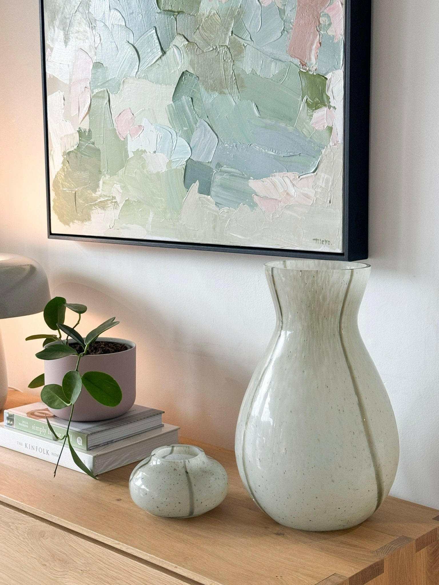 GlobeWest Boden Stripe Vase tall sage glass with delicate stripes on wooden surface next to small planter and abstract painting