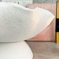 Close-up of a white ceramic Ripple White Pedestal Bowl with a textured exterior and smooth interior on a countertop.