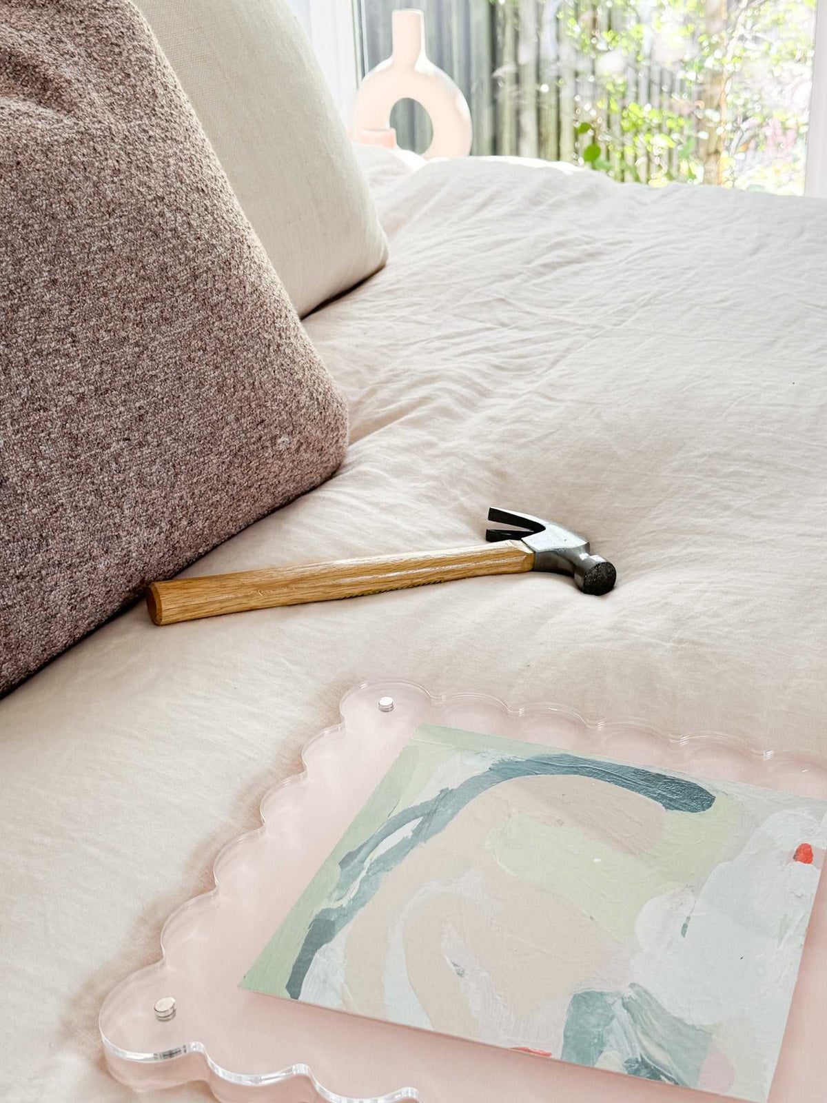 norsu STUDIO scalloped magnetic photo frame in blush with abstract art on bed with pillows and hammer nearby