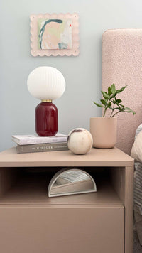 norsu STUDIO scalloped magnetic photo frame in blush background on wall above bedside table with lamp and plant