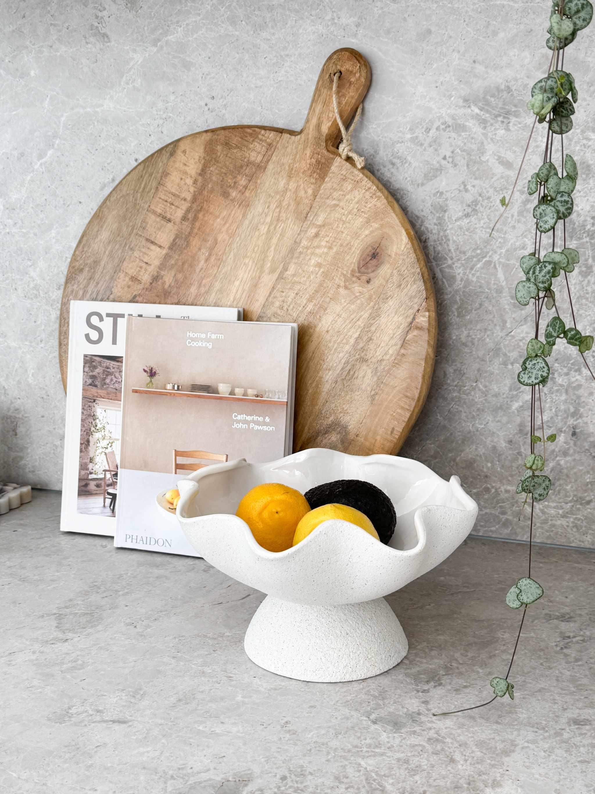 Ripple White Pedestal Bowl ceramic fruit bowl with glossy interior and textured exterior on countertop with fruits
