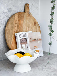 Ripple White Pedestal Bowl ceramic fruit bowl with glossy interior and textured exterior holding lemons and mangoes on a modern kitchen countertop