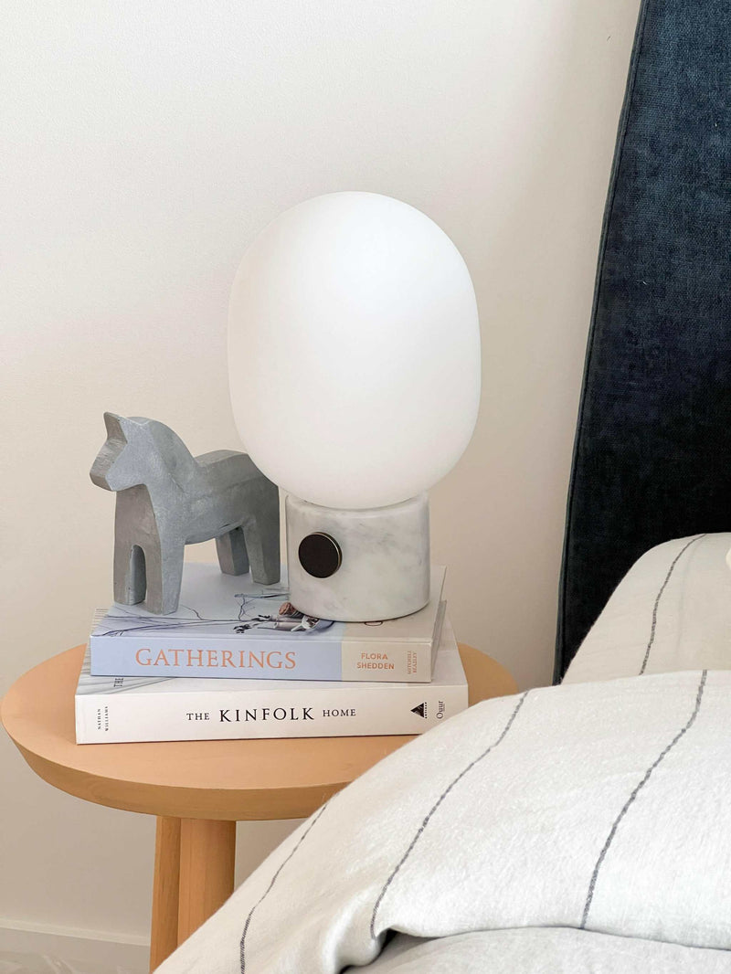 Menu JWDA Marble Lamp with Carrara marble base and white glass shade on wooden side table next to bed
