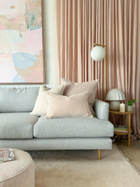 norsuHOME Cushion Parissi Shell in beige tones on light grey sofa with soft pink curtains and modern decor