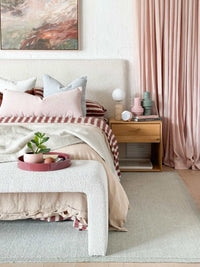 Vintage alarm clock with blush color, gold accents, and retro design on bedside table in cozy bedroom setting