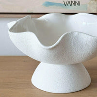 Ripple white ceramic pedestal bowl with glossy interior and textured exterior on wooden surface