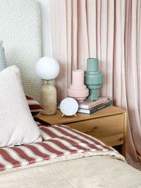 Maisie Silent Tick Alarm Clock in blush with gold accents on wooden bedside table in cozy bedroom setting