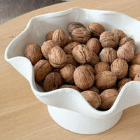 Ripple White Pedestal Bowl ceramic with textured exterior holding walnuts on wooden table