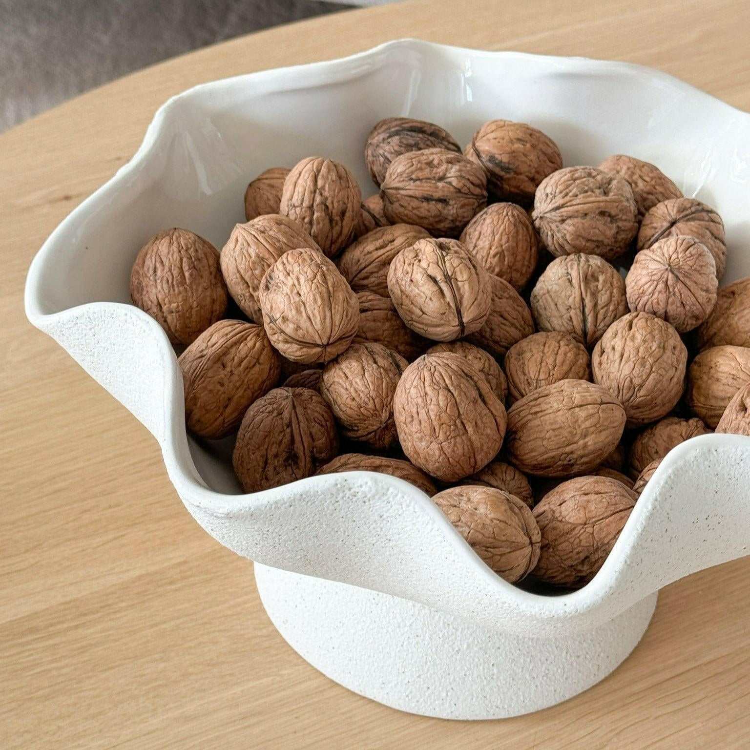 Ripple White Pedestal Bowl ceramic with textured exterior holding walnuts on wooden table