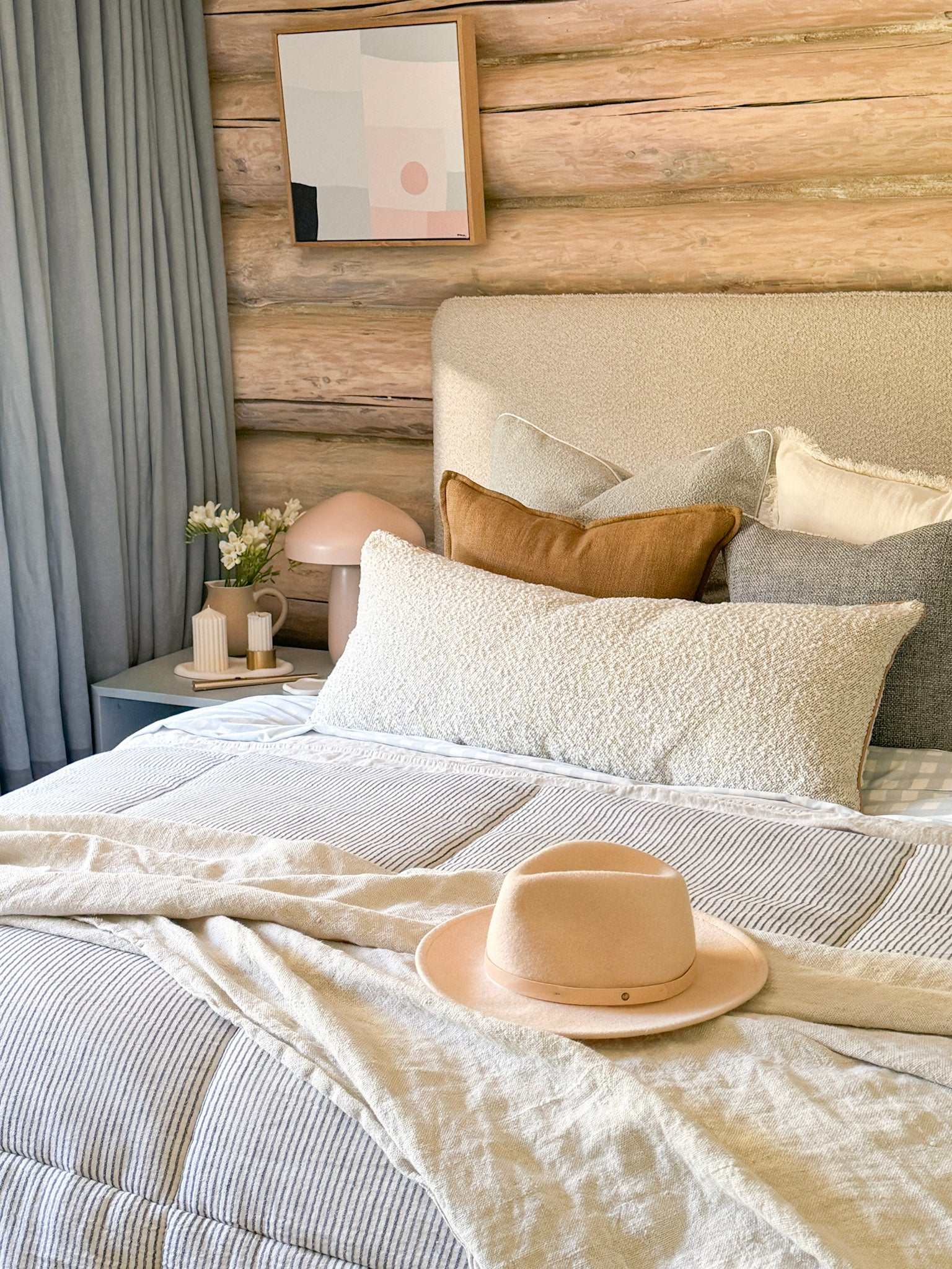 Baya Flaxmill Cushion in fenugreek soft clay linen with flange edge on bed in cozy rustic bedroom setting