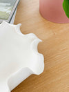 White Lottie Decorative Bowl with ruffled edges and matte finish on wooden surface
