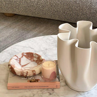 CoTheory Marble Tray Solstice small brown Calacatta with sculptural curves on marble table next to candle and vase