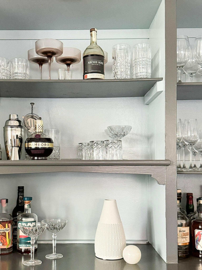 CoTheory Orbit Table Sculpture small white onyx sphere on shelf with glassware and bottles