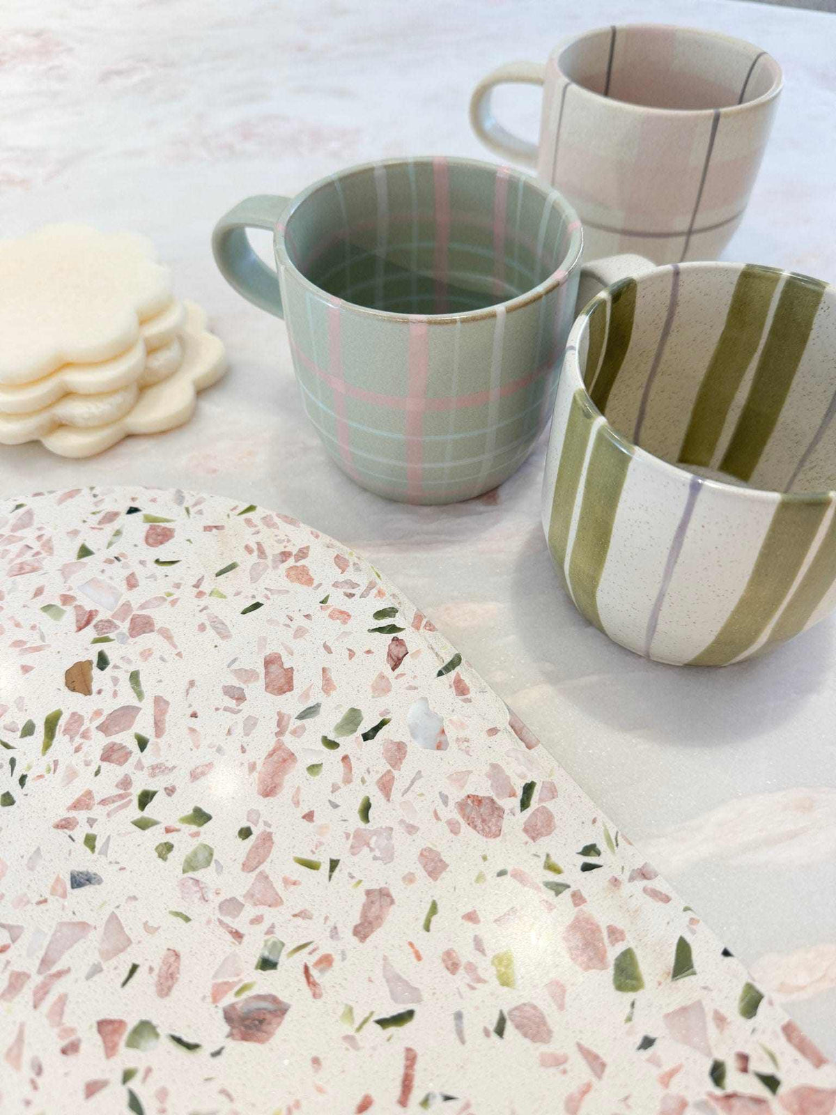 Set of Robert Gordon Hand-Painted Mugs with unique olive stripe, pastel check, and neutral striped designs on a kitchen surface