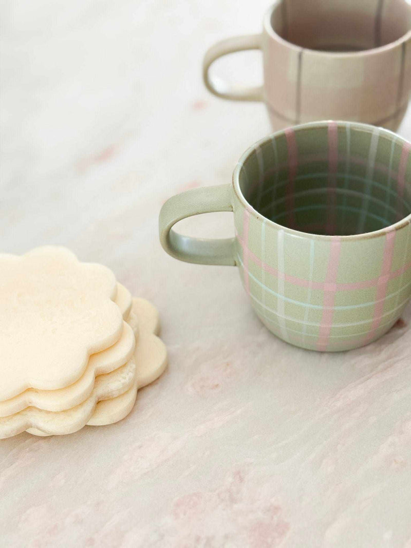 Robert Gordon hand-painted ceramic mug with blush and grey tartan design next to flower-shaped cookies on marble surface