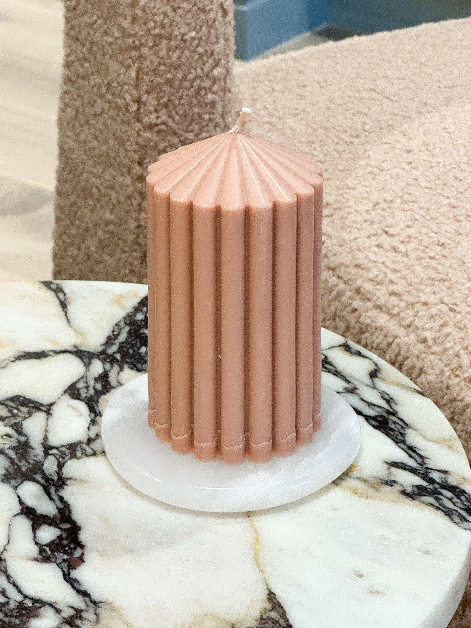 Black Blaze white onyx marble coaster with pink fluted candle on marble table
