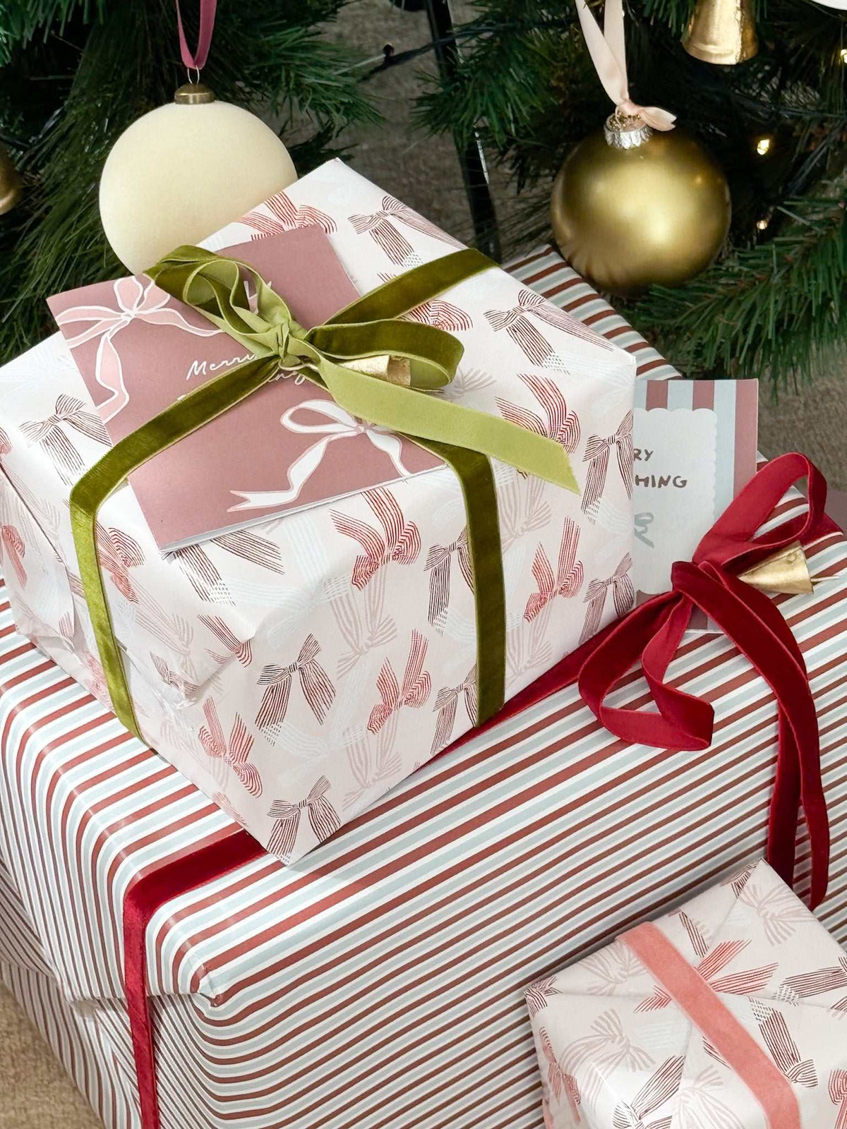 norsu Studio Christmas Wrapping Paper jumbo roll with festive stripe and bow designs on wrapped gifts under tree