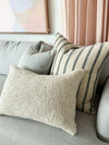 Baya Cyprian Oblong Cushion in warm oatmeal on a grey sofa with textured cotton and linen blend fabric