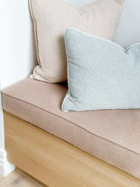 norsu Studio Cushion in powder blue boucle with white leather piping on a beige seat cushion with wooden base, showcasing handcrafted luxury and plush feather-down filling