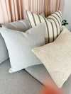norsu Studio Cushion in powder blue boucle with white leather piping on a grey sofa with decorative pillows