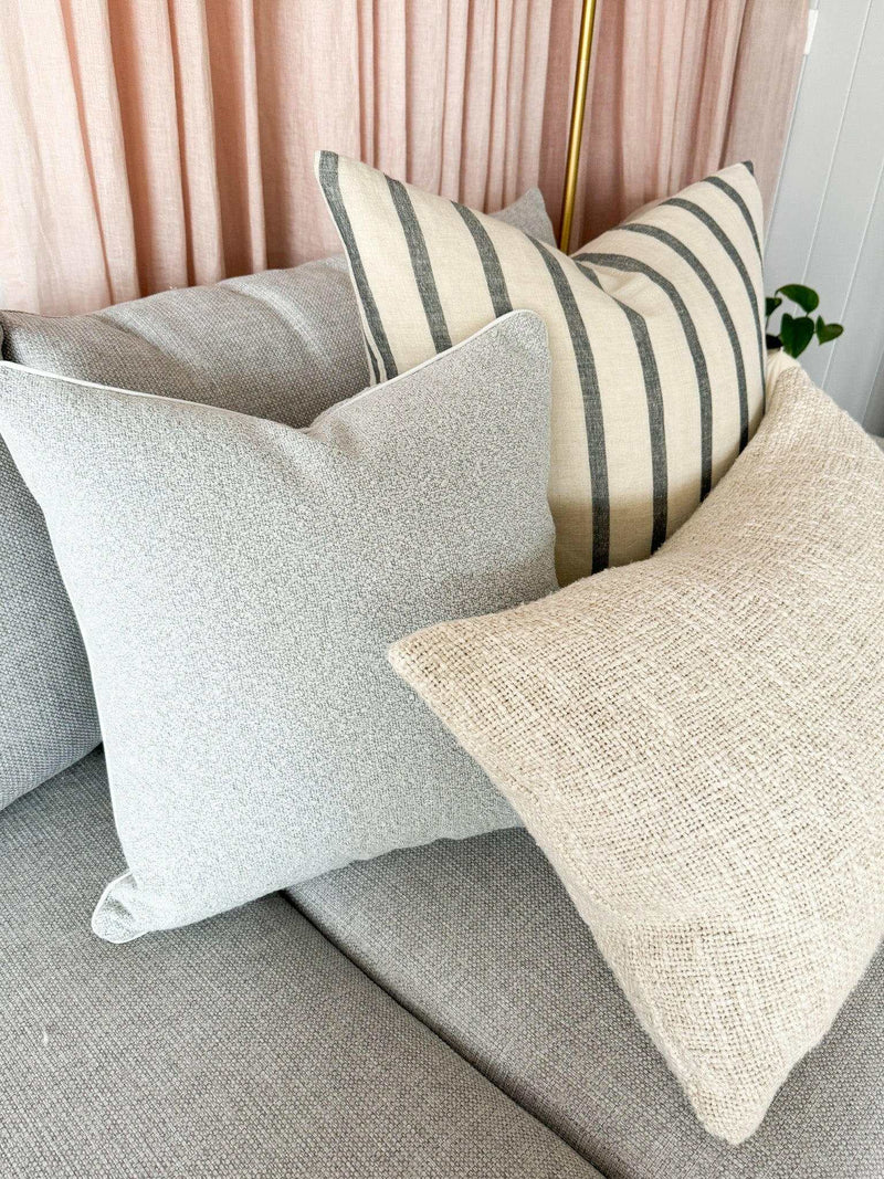Baya Cyprian Oblong Cushion in oatmeal with soft textured yarn on a grey sofa with other cushions