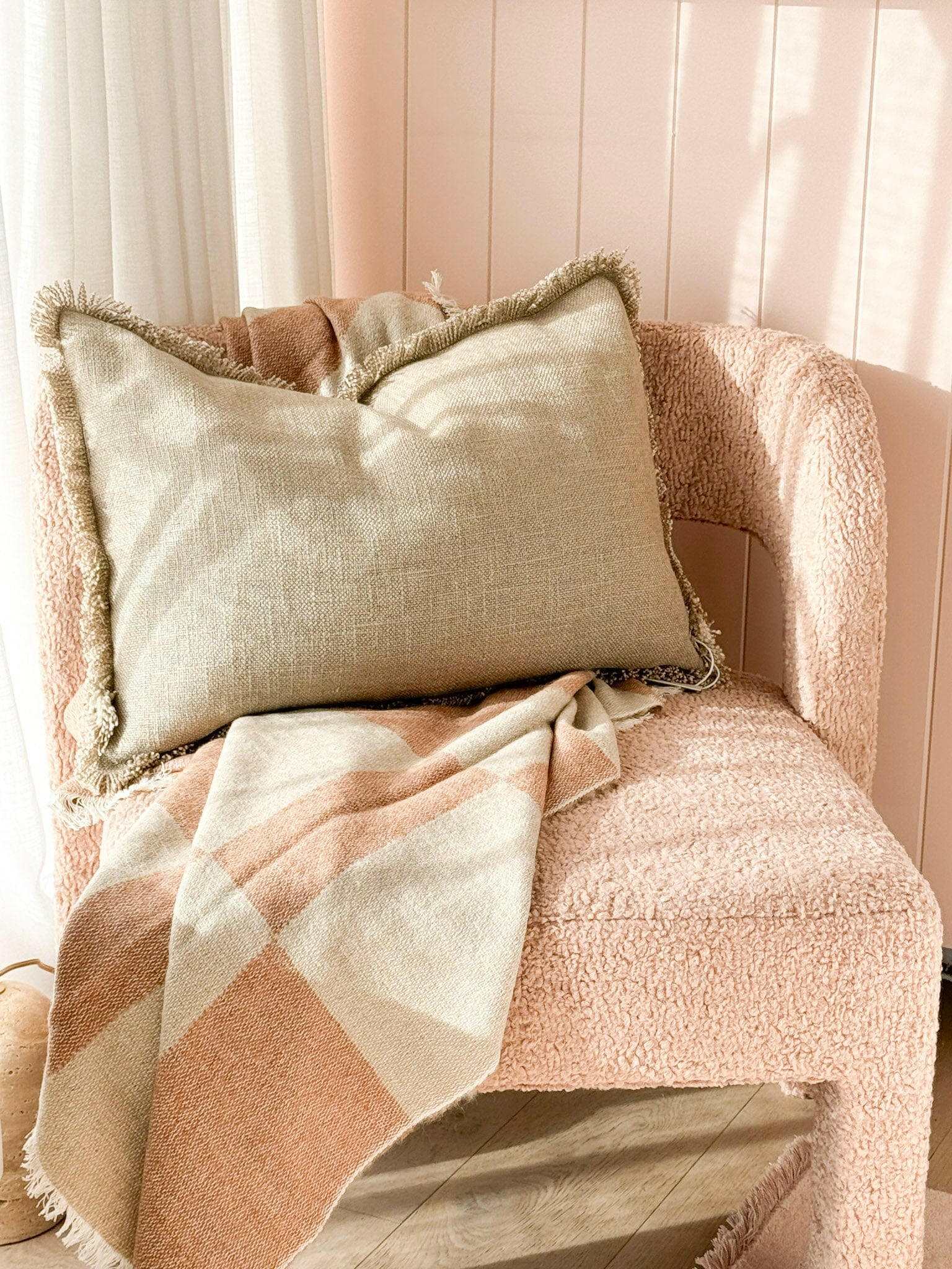 Baya Dover Cushion natural lumbar pillow with fringed edges on textured pink chair