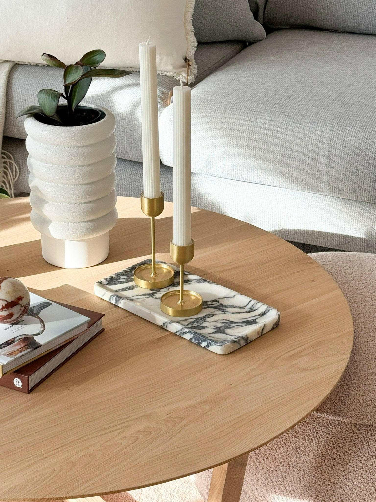 Linea Rectangle Marble Tray made of Calacatta Viola marble with violet veins, displayed on a wooden table with gold candlesticks and a modern white planter