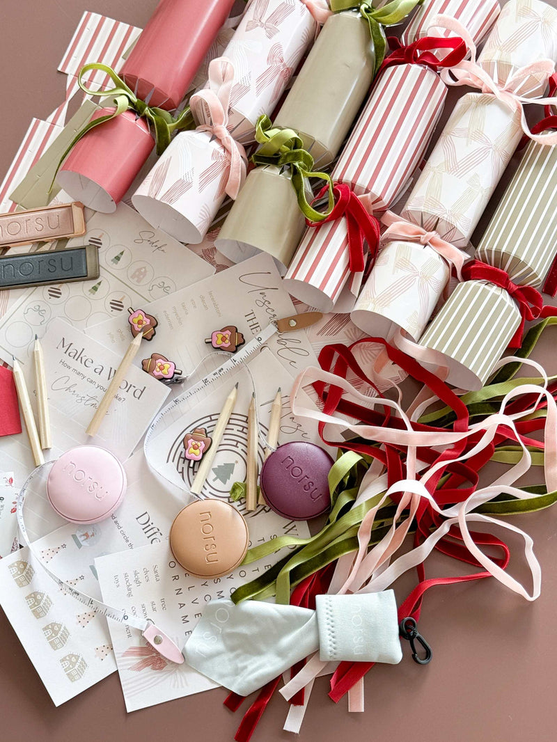 norsu Studio DIY Christmas Crackers set of six with velvet ribbons, gifts, paper hats, and festive decorations on a table