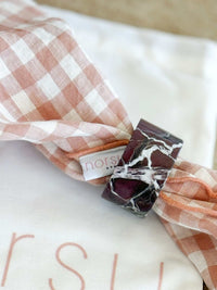 norsu STUDIO Marble Circular Napkin Ring in Rosso Levanto with deep burgundy and white veining on a pink checkered napkin