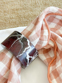 norsu STUDIO Marble Circular Napkin Ring in Rosso Levanto with deep burgundy and white veining on checkered napkin