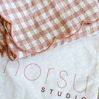 Folded checkered fabric on a white surface with 'norsu Studio' branding.