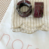 Set of 4 norsu Studio linen napkins in oatmeal stripe with scalloped edges and marble napkin rings on fabric bag
