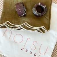 Two marbled stones on a green fabric napkins with 'norsu studio' branding.