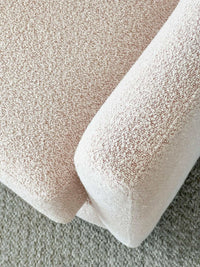 Close-up of blush boucle fabric texture on norsu Studio Swivel Chair armrest and seat cushion