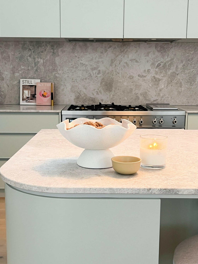 Minimalist kitchen bench styled like a pro with decorative bowl, candle, and cup on marble surface