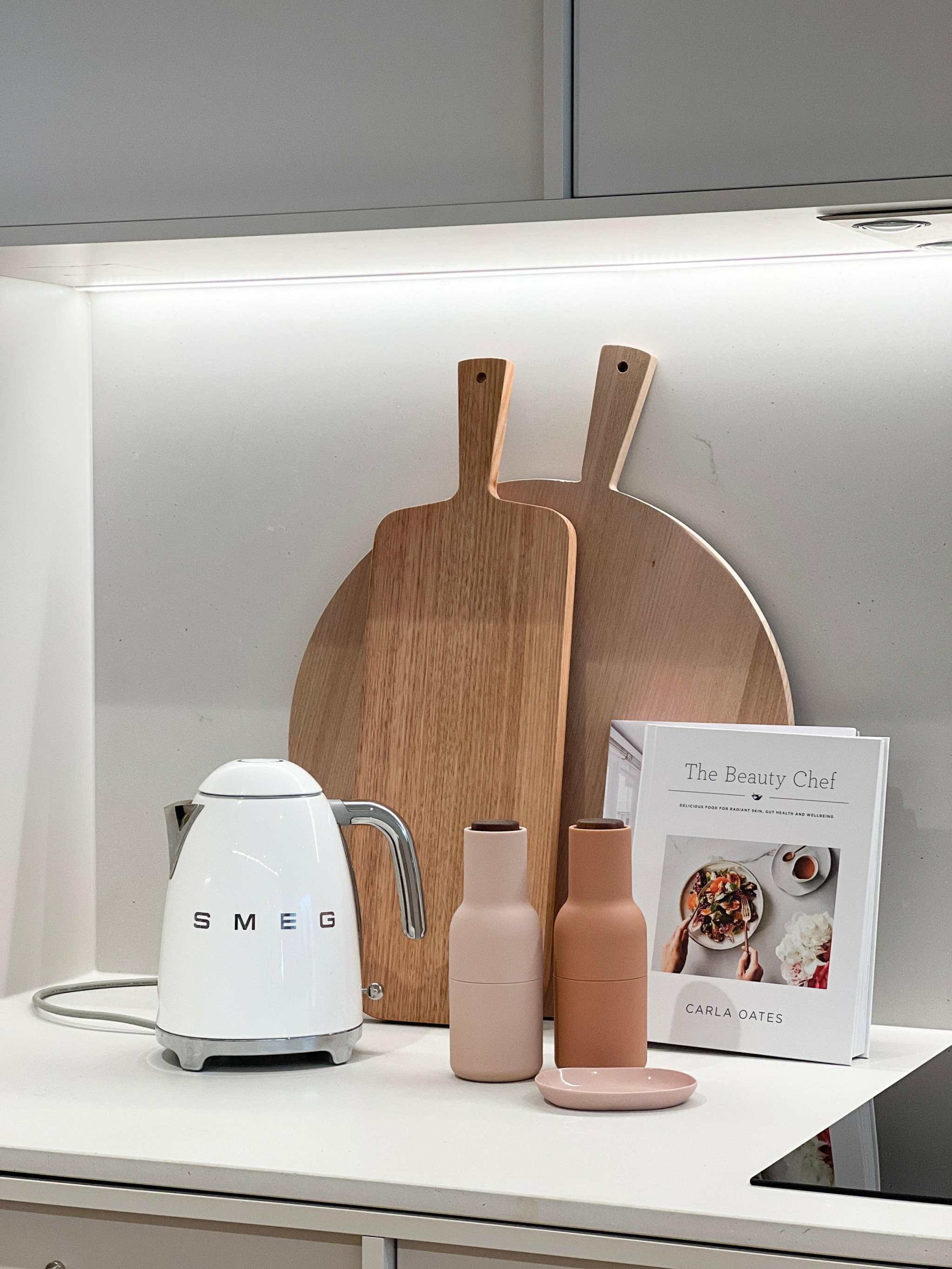 Stylish kitchen bench setup with SMEG kettle, wooden cutting boards, decorative bottles, and cookbook for Kitchen Bench like a Pro eService