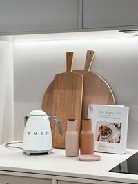 Stylish kitchen bench setup with SMEG kettle, wooden cutting boards, decorative bottles, and cookbook for Kitchen Bench like a Pro eService