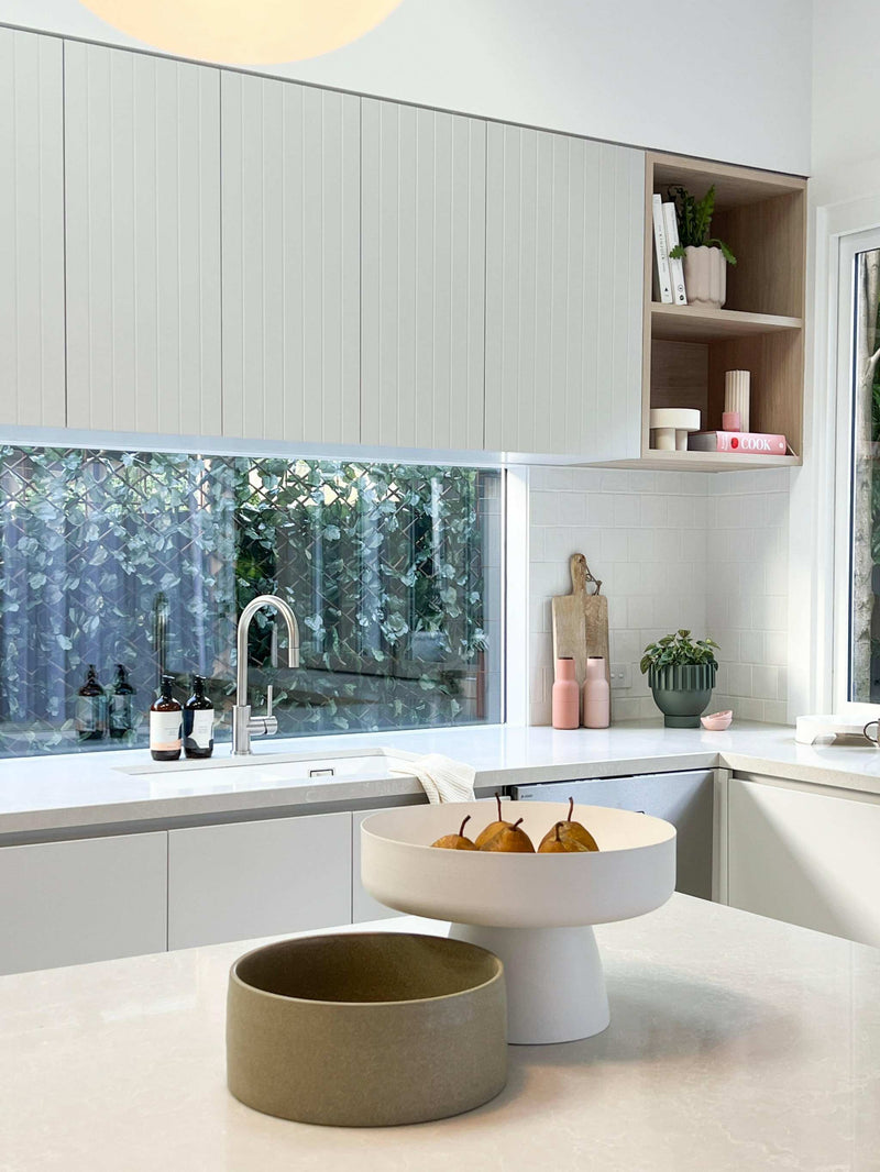 modern kitchen bench styled with decorative bowls and minimalist decor near window