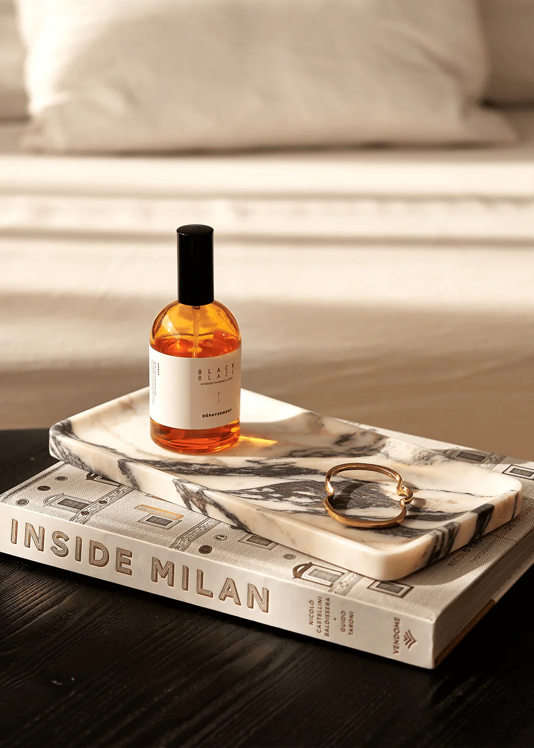 Linea Rectangle Marble Tray in Calacatta Viola marble with violet veins, holding perfume and jewelry on a book.