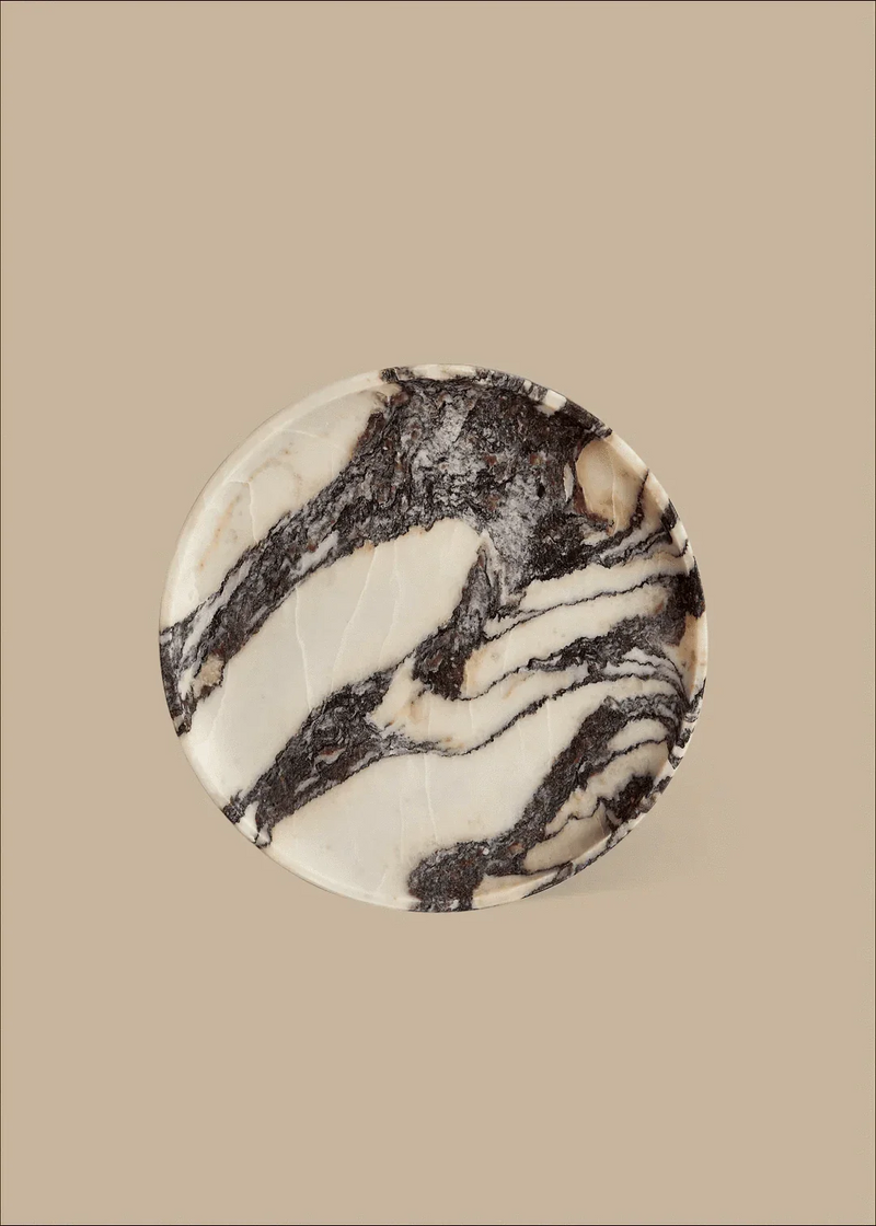 Linea Round Marble Tray made of Calacatta Viola marble with unique black and white veining on a beige background