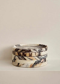 Stacked Linea Round Marble Trays in black and white Calacatta Viola marble with natural veining and smooth round edges.