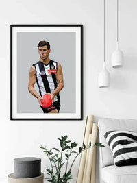 Framed Dom Gauci Kids Art Print of Nick Daicos in Collingwood FC AFL uniform holding a football on grey background