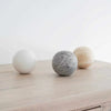 CoTheory Orbit Sphere Table Sculpture in beige travertine on wooden surface, symbolizing harmony and balance
