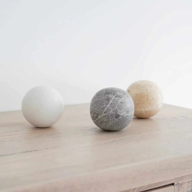 CoTheory Orbit Sphere Table Sculpture in beige travertine on wooden surface, symbolizing harmony and balance