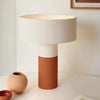 POTT Lighting Terra Table Lamp in matte white and dark terracotta with textured ceramic base and white cylindrical shade on a neutral surface