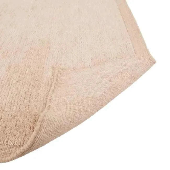 Close-up of GlobeWest Bower Frame Rug in rose color showing hand-woven wool texture and folded corner