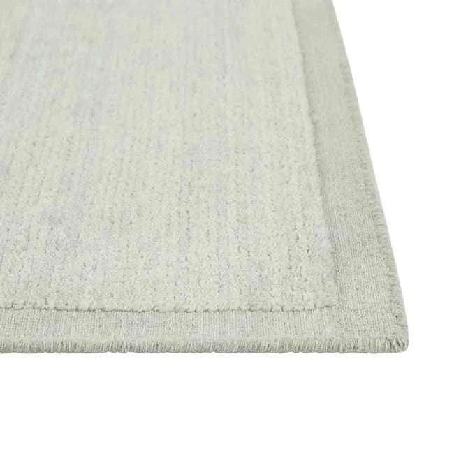 Close-up of GlobeWest Bower Frame Rug in seafoam color with hand-woven wool texture and simple border design.