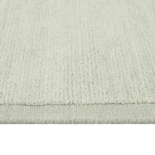 Close-up of the hand-woven GlobeWest Bower Frame Rug in seafoam wool with textured surface and subtle border detail.